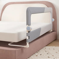 Barrière de lit bébé pliable grise installée sur lit adulte rose, dispositif de sécurité anti chute