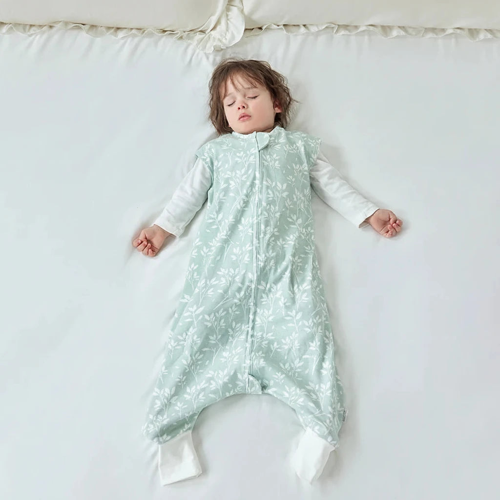 Enfant allongé portant la gigoteuse à pied vert sauge