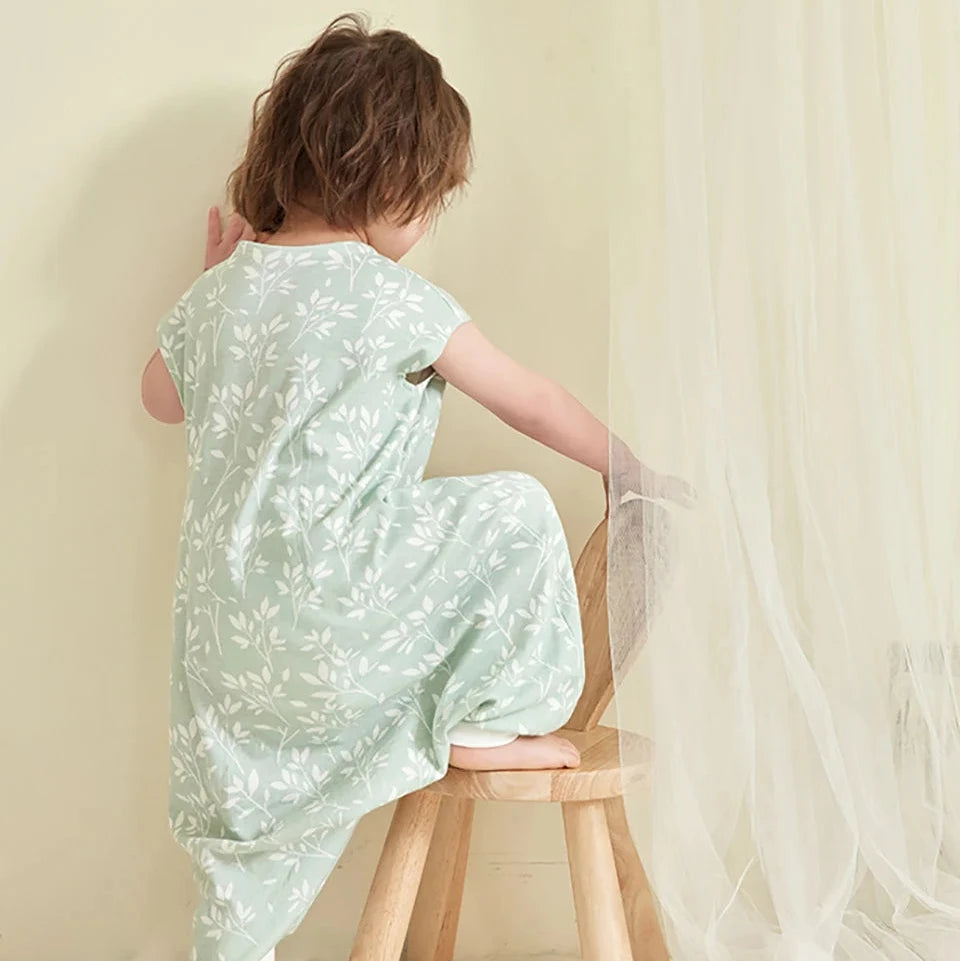 Enfant assis sur le tabouret, deuxième vue, portant la gigoteuse à pied vert sauge